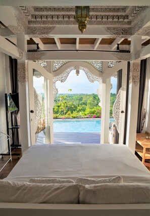 A bedroom with a large bed, a view of a swimming pool, and intricate ceiling designs. - Mambo Hill Resort (Penida Island)