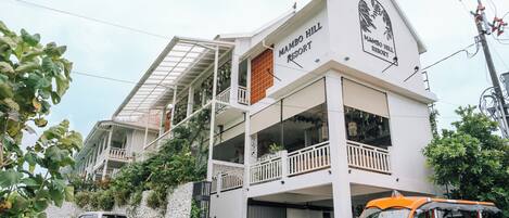 Un edificio de dos pisos con balcones y un letrero que dice "Mambo Hill Resort".