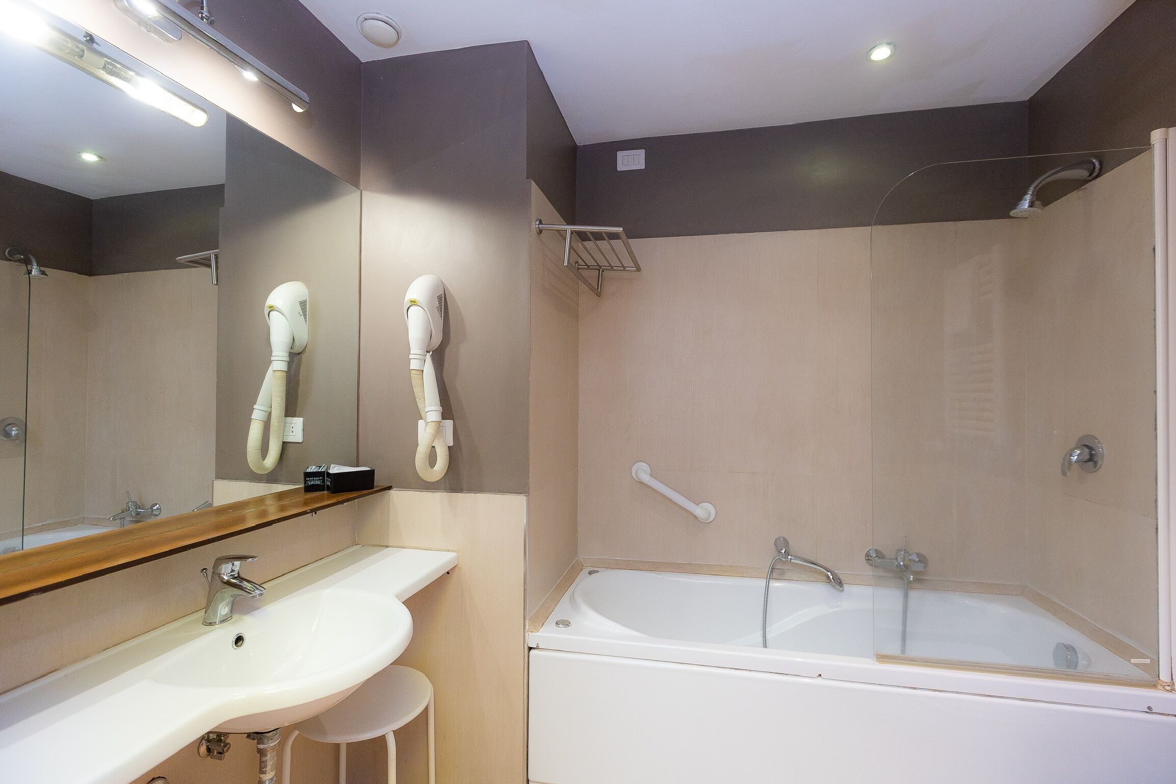 A modern bathroom with a sink, mirror, hairdryer, and shower.