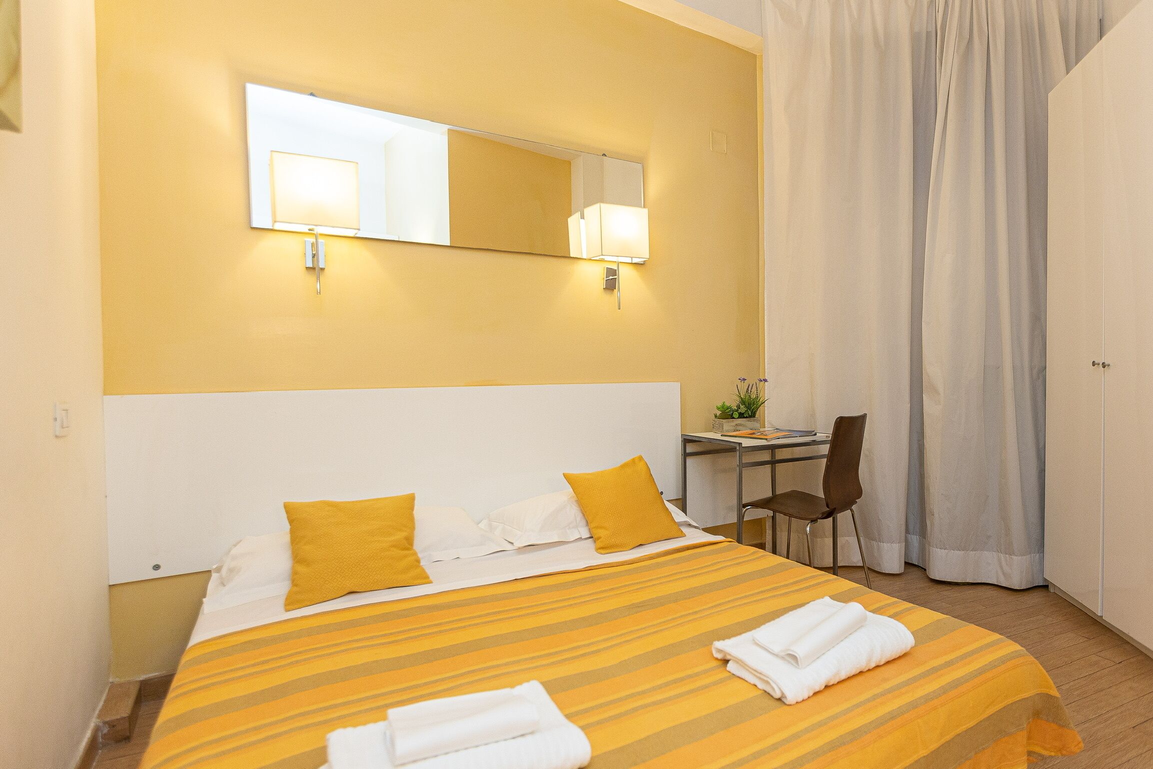 Una habitación de hotel con una cama, un escritorio y una silla.