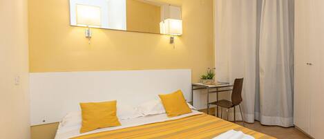 Una habitación de hotel con una cama, un escritorio y una silla.