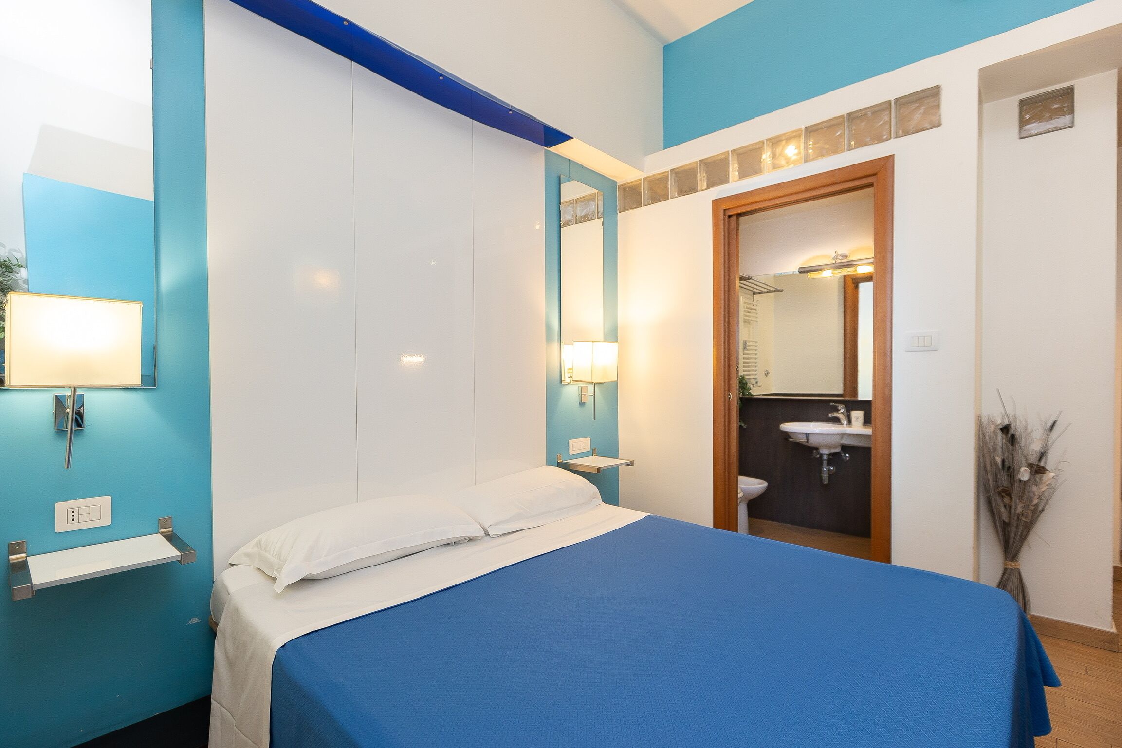 Un dormitorio con cama, mesita de noche y espejo.