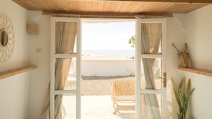 An open door leading to a beach view, with a wicker chair and a potted plant inside. - Dreamsea Surf Camp Imsouane (Imsouane)