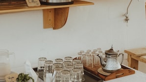 A coffee station with a coffee maker, a menu board, and various drinkware. - Dreamsea Surf Camp Imsouane (Imsouane)