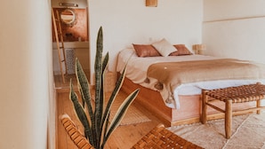A bedroom with a wooden ceiling, a bed with a brown blanket, a bedside table, and a large plant. - Dreamsea Surf Camp Imsouane (Imsouane)