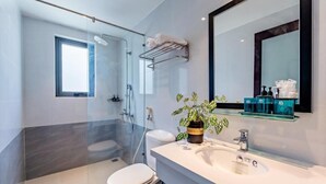 A modern bathroom with a glass-enclosed shower, a toilet, a sink with a mirror, and a potted plant. - Lacasa Old Town Villa (Da Nang)