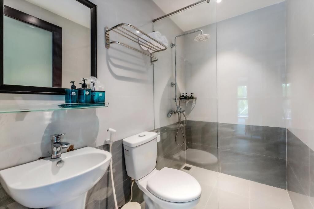 A modern bathroom with a glass shower enclosure, a white sink, and a toilet.