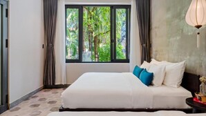 A bedroom with a large bed, a view of greenery outside, and a hanging light fixture. - Lacasa Old Town Villa (Da Nang)