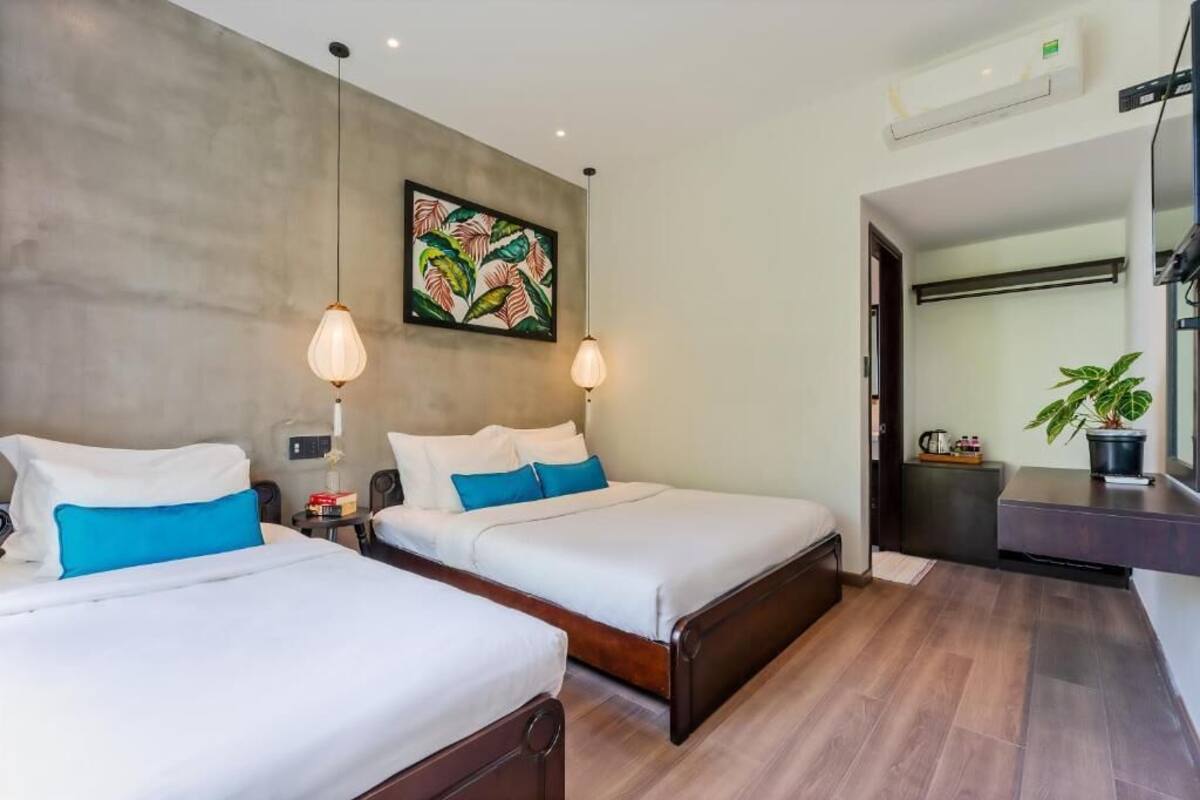 A hotel room with two beds, a large abstract painting, a potted plant, and a modern air conditioning unit.