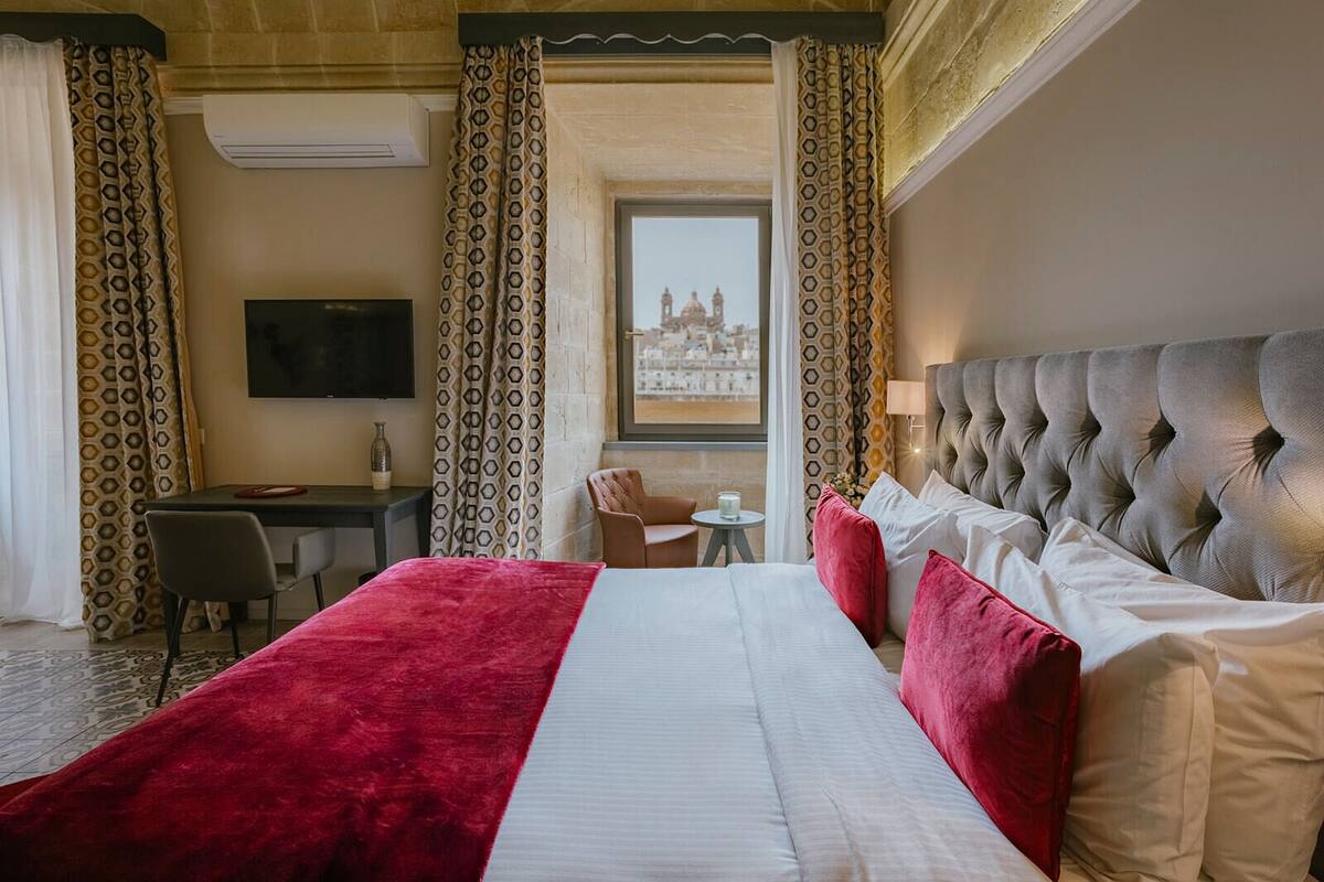 A hotel room with a large bed, a desk, a chair, and a television.