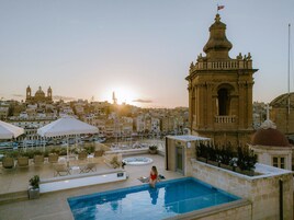 Uma área de piscina no terraço com vista para a paisagem urbana e um edifício com cúpula em destaque.