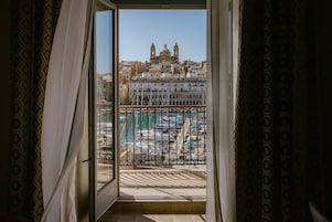 Uma varanda com vista para um porto de iates e um edifício histórico com cúpulas.