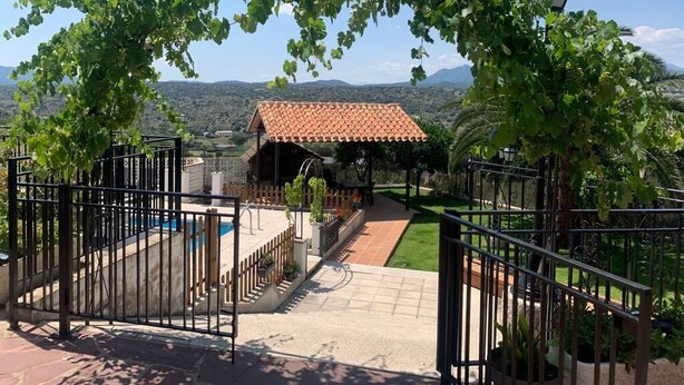 Une villa avec un toit en tuiles, une piscine et une vue sur les montagnes.