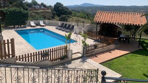 Une piscine avec des chaises longues, une pergola et une vue sur la campagne.