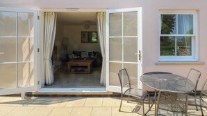 A two-story building with a balcony, a patio area with a table and chairs, and a large window. - 5 Combehaven (Salcombe)