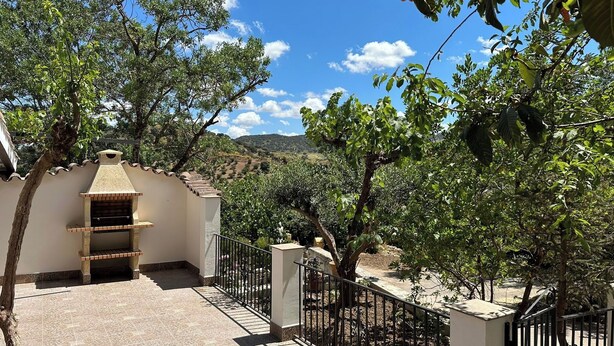 Una vila amb un pati enrajolat, una petita xemeneia de maó i una tanca de metall.
