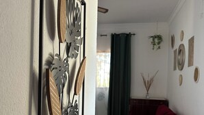 Un saló amb un sofà vermell, una obra decorativa penjada a la paret i una finestra amb cortines.