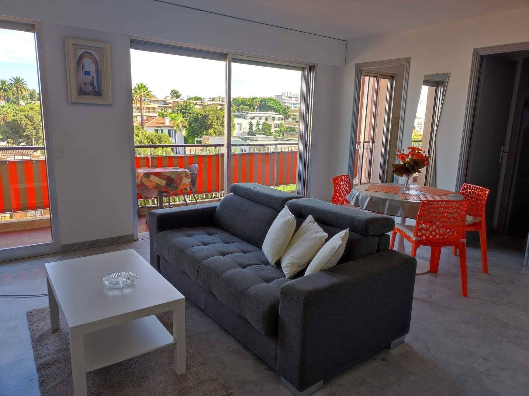 Een moderne woonkamer met een grijze bank, een witte tafel en rode stoelen.