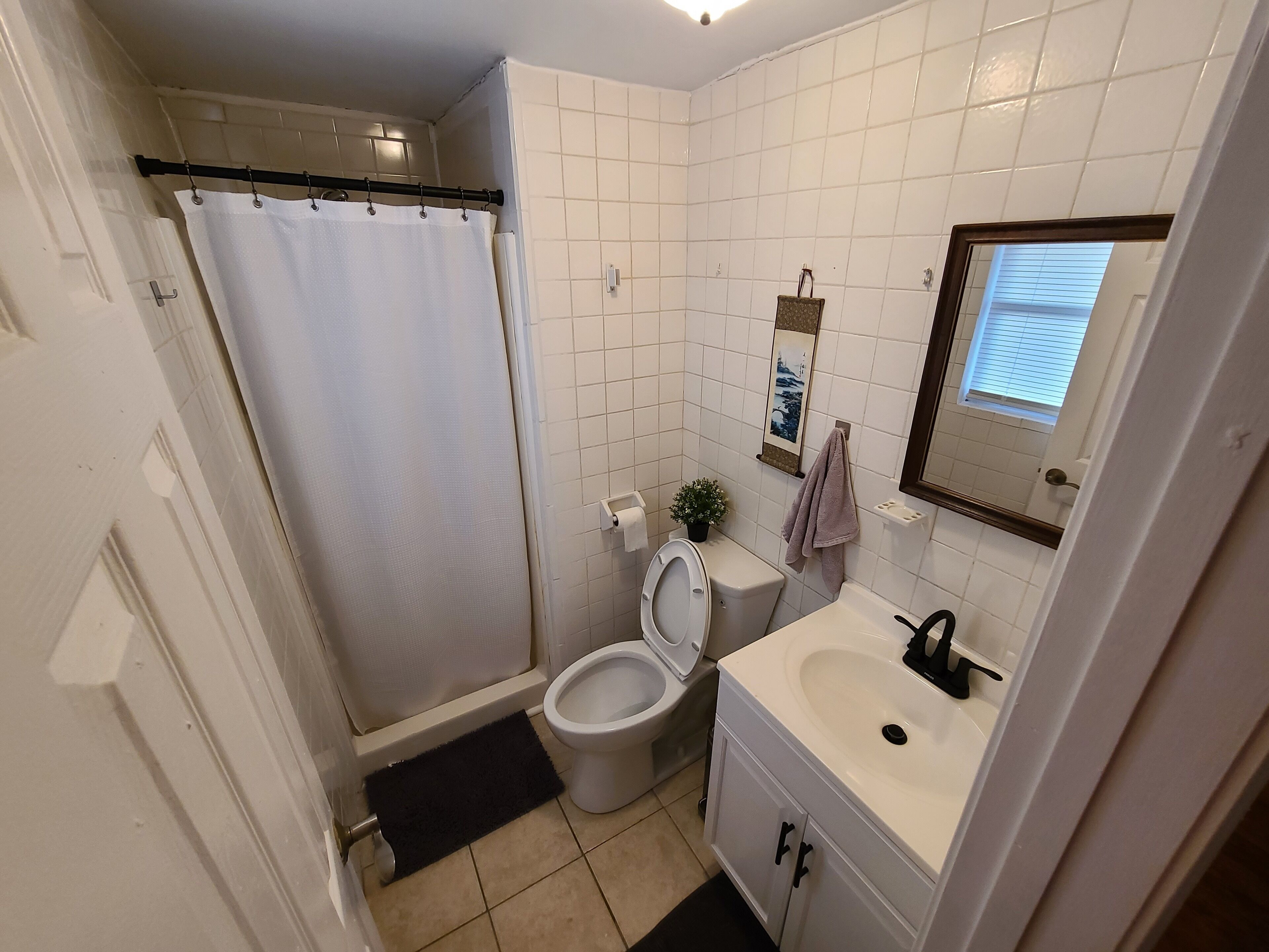 Een kleine badkamer met toilet, wastafel en douchegordijn.