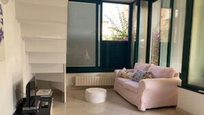 A modern living room with a pink sofa, a coffee table, and a TV on a stand.