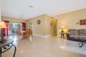 Cozy living area with a dining table for four, comfortable sofa, and glass coffee table.