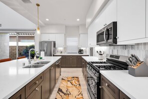 A modern kitchen with stainless steel appliances, a central island, and a view to the outside. - Sparkling New 3 Bed 3 Bath Private Pool Home With Incredible Views #260292 (La Quinta)