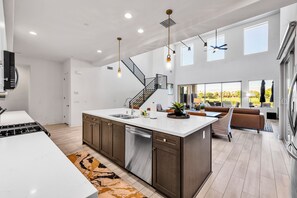 Une cuisine moderne dotée d’un îlot central, d’appareils électroménagers en acier inoxydable et d’un escalier menant à un niveau supérieur.
