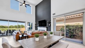 Un salón amplio con una gran mesa de madera, asientos cómodos, un televisor de pantalla plana y una chimenea.