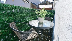 A small outdoor seating area with a round table and two wicker chairs, surrounded by a green hedge. - Monopoly Breeze House (Brighton and Hove)