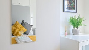 A modern bathroom with a white vanity, a mirror, a potted plant, and a framed artwork on the wall. - Monopoly Breeze House (Brighton and Hove)