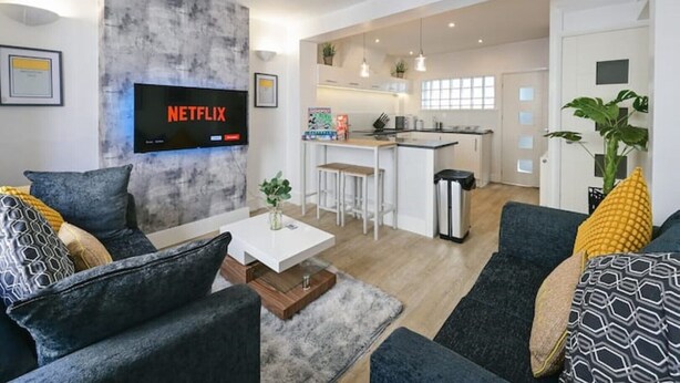A modern living room with a flat-screen TV, a kitchen in the background, and a dining area. - Monopoly Breeze House (Brighton and Hove)