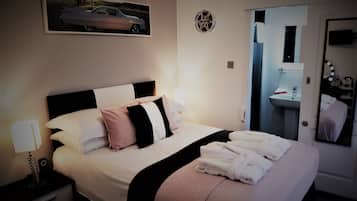 A hotel room with a bed, nightstands, a mirror, and a bathroom visible through an open door.