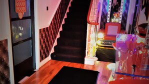 A staircase with a black carpet leading to a room with a red chair and a table.