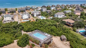 An aerial view of a coastal residential area with houses, a swimming pool, and a beach. - Endless Summer: Direct Beach Access | Ocean Views (Duck)