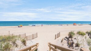 A beach with wooden walkways leading to the shore, a sandy beach, and a clear blue sky. - Endless Summer: Direct Beach Access | Ocean Views (Duck)