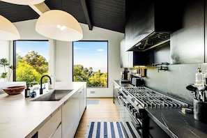 A modern kitchen with a large island, a gas stove, and a view of the outdoors.
