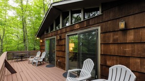 Una terraza de madera con mobiliario exterior y puerta de cristal.