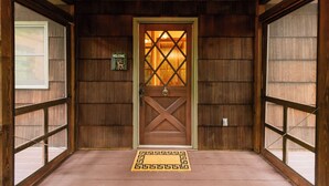 Una puerta de madera con un panel de vidrio, un letrero de bienvenida, un felpudo y un piso de madera.