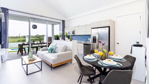 Ein modernes Wohnzimmer mit Sofa, Couchtisch und Essbereich mit Tellern und Gläsern.
