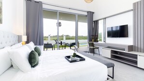 Ein modernes Hotelzimmer mit einem großen Bett, einem Fernseher und einem Balkon mit Sitzgelegenheit.