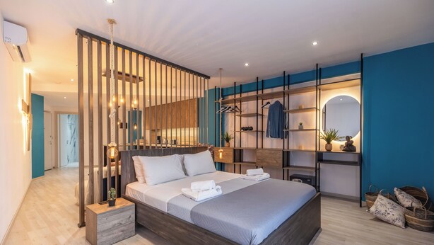 A modern bedroom with a large bed, wooden headboard, and a built-in wardrobe with shelves and a mirror. - Semiso Beach Suite 9 (rethymno)