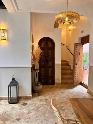 Staircase leads to an upper level, with a dining area featuring a wooden table and chairs.