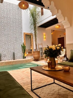Relax by the pool in a serene space with a comfortable sofa, elegant vase, and lush greenery.