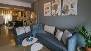 A modern living room with a grey sectional sofa, a white coffee table, and abstract art on the wall. - Seafront Kalamata Haven - Blue Luxury Suite (Kalamata)