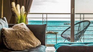 A balcony with a view of the sea, a sofa with a fluffy pillow, and a chair. - Seafront Kalamata Haven - Blue Luxury Suite (Kalamata)