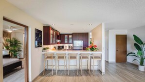 A modern kitchen with a central island, bar stools, and a microwave.