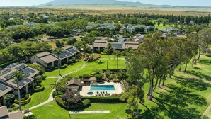 An aerial view of a residential area with houses, a swimming pool, and a mountain in the background.