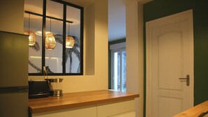 A modern kitchen with a wooden countertop, a built-in stove, and pendant lights.