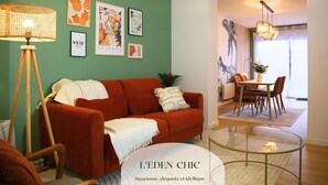 A modern living room with a red sofa, a glass coffee table, and a dining area with a table and chairs.
