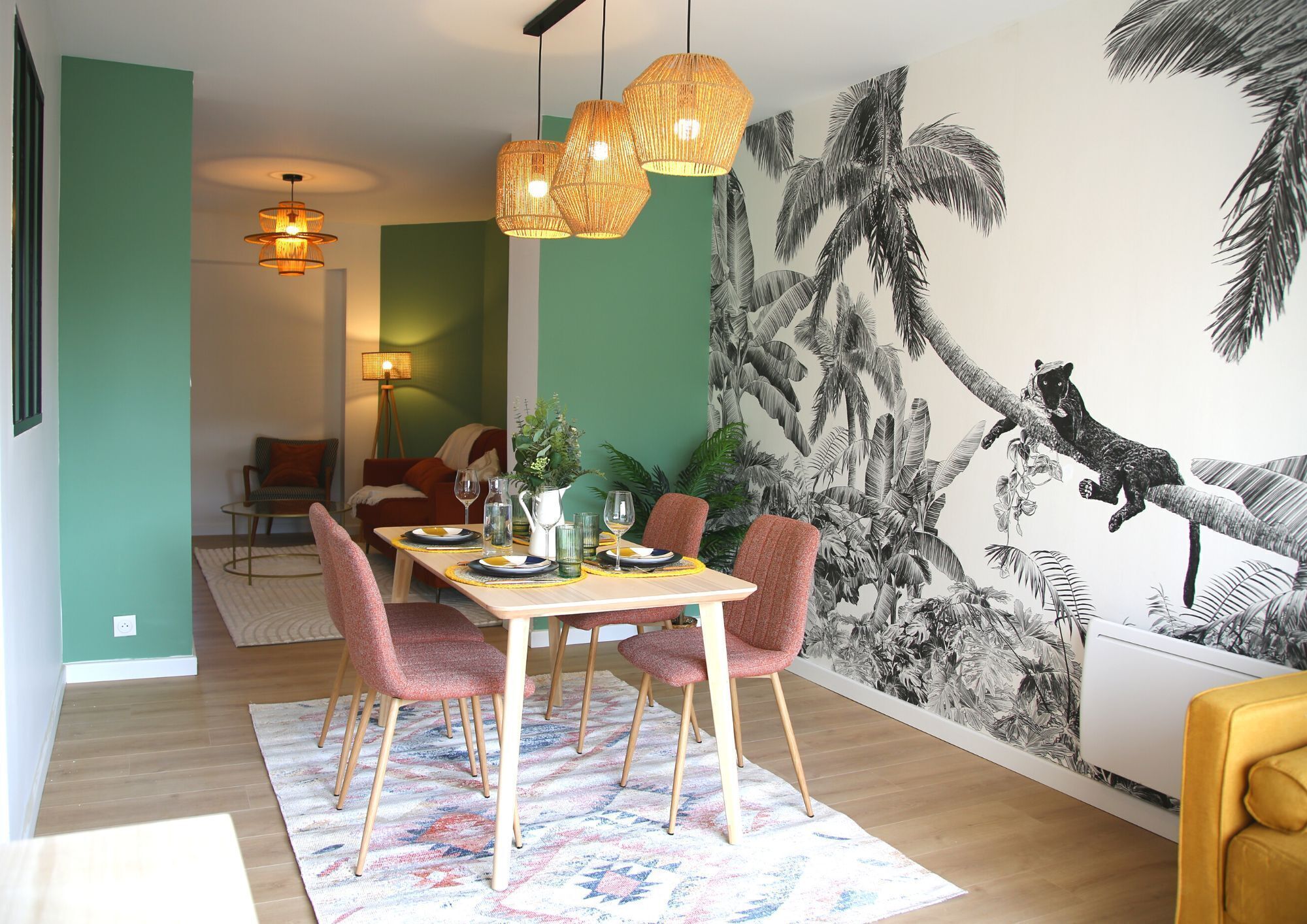 A dining area with a table set for four, surrounded by chairs, and a mural of a jungle scene on the wall.